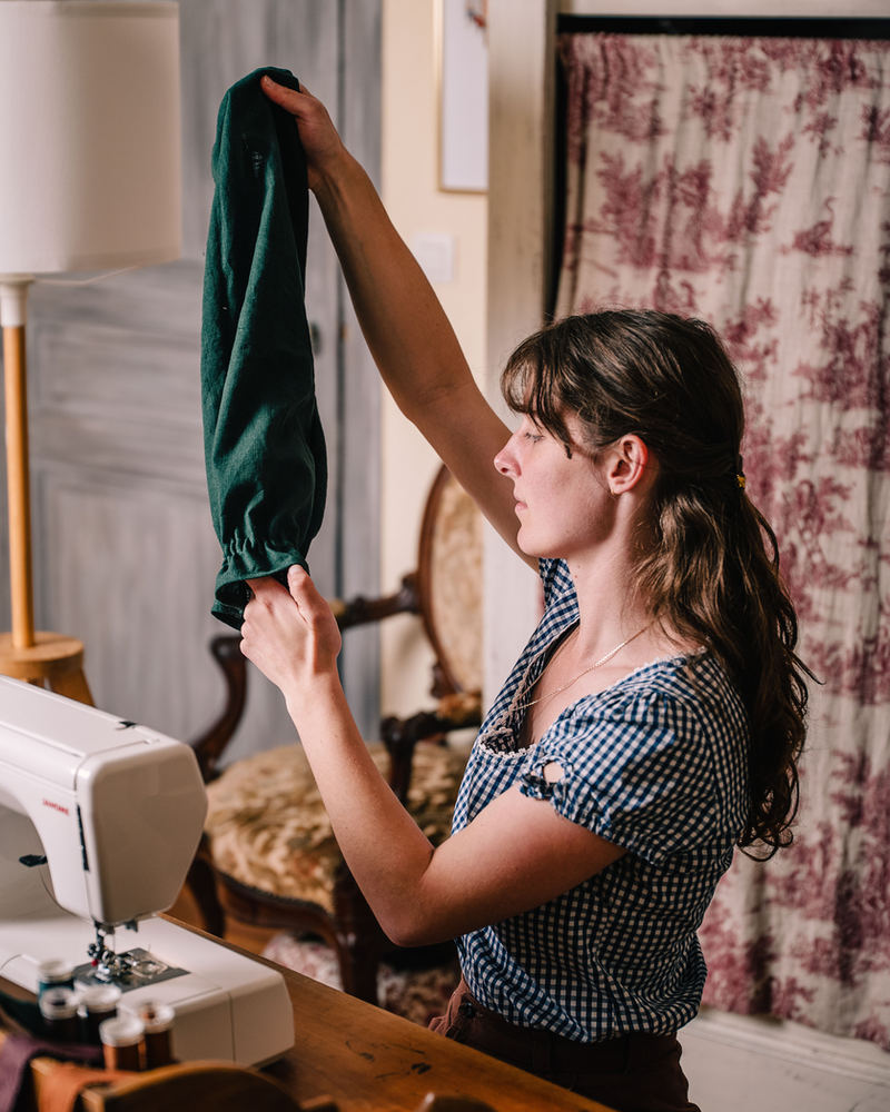 Manon tient un tissu vert devant sa machine à coudre